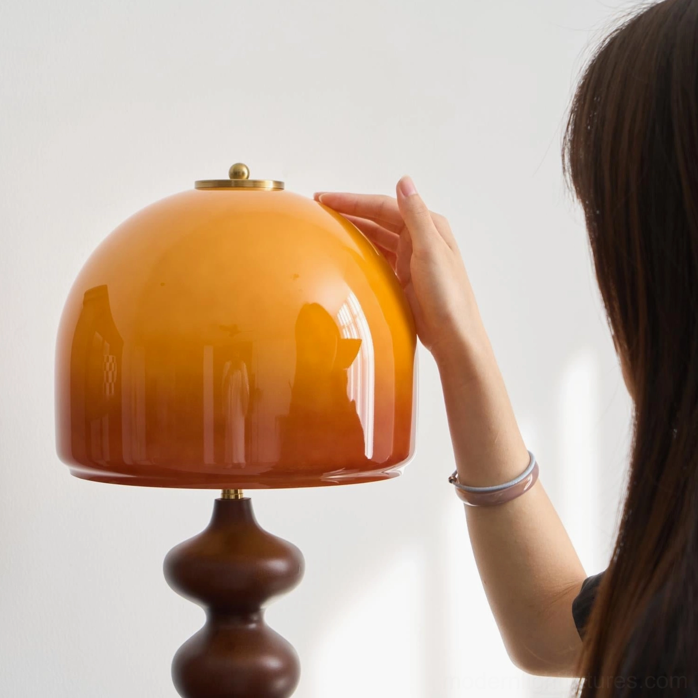 Close-up of Willow table lamp glass shade with hand contact, warm amber light diffusion detail