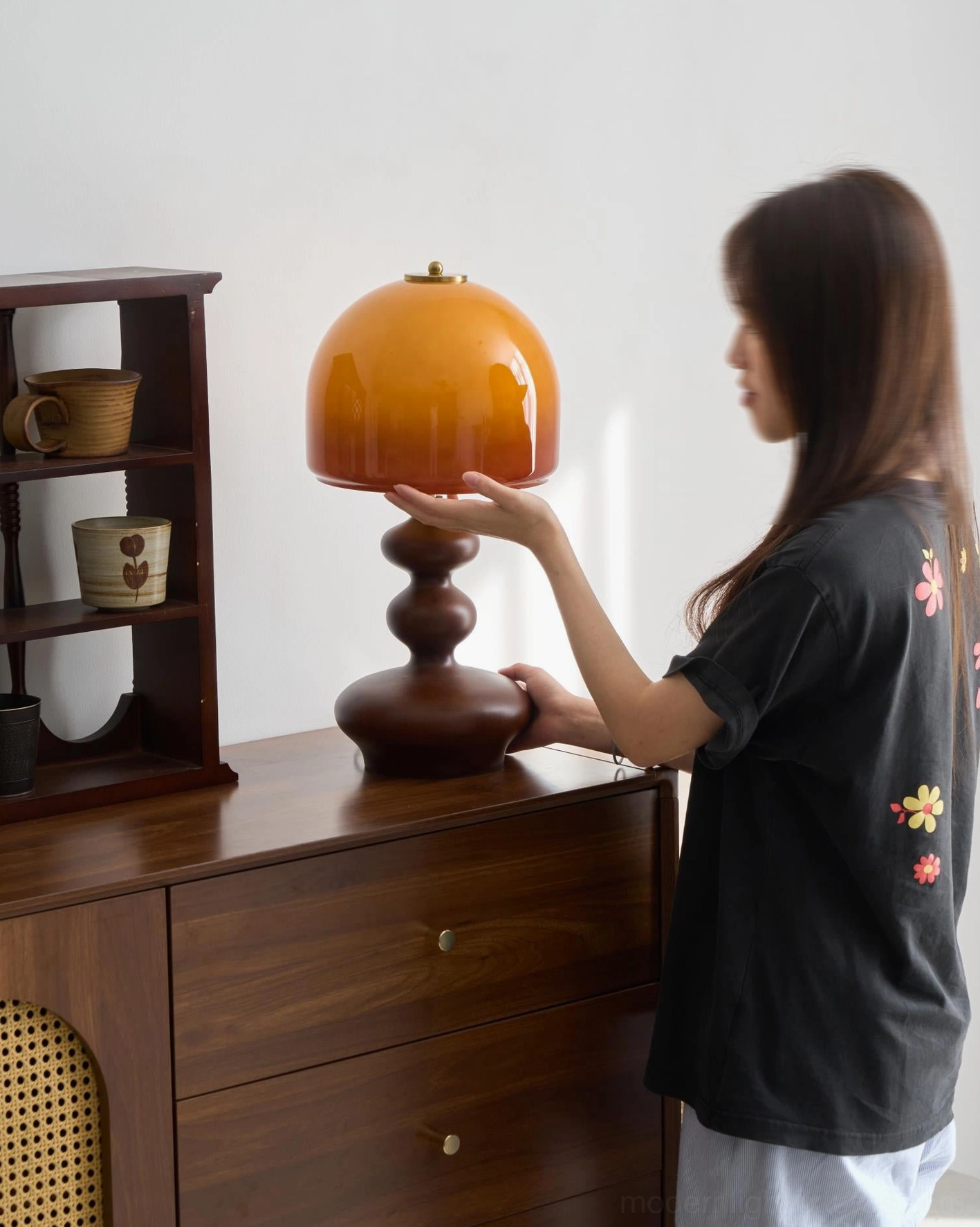 Woman adjusting Willow table lamp caramel glass dome, home interior scene with side table display