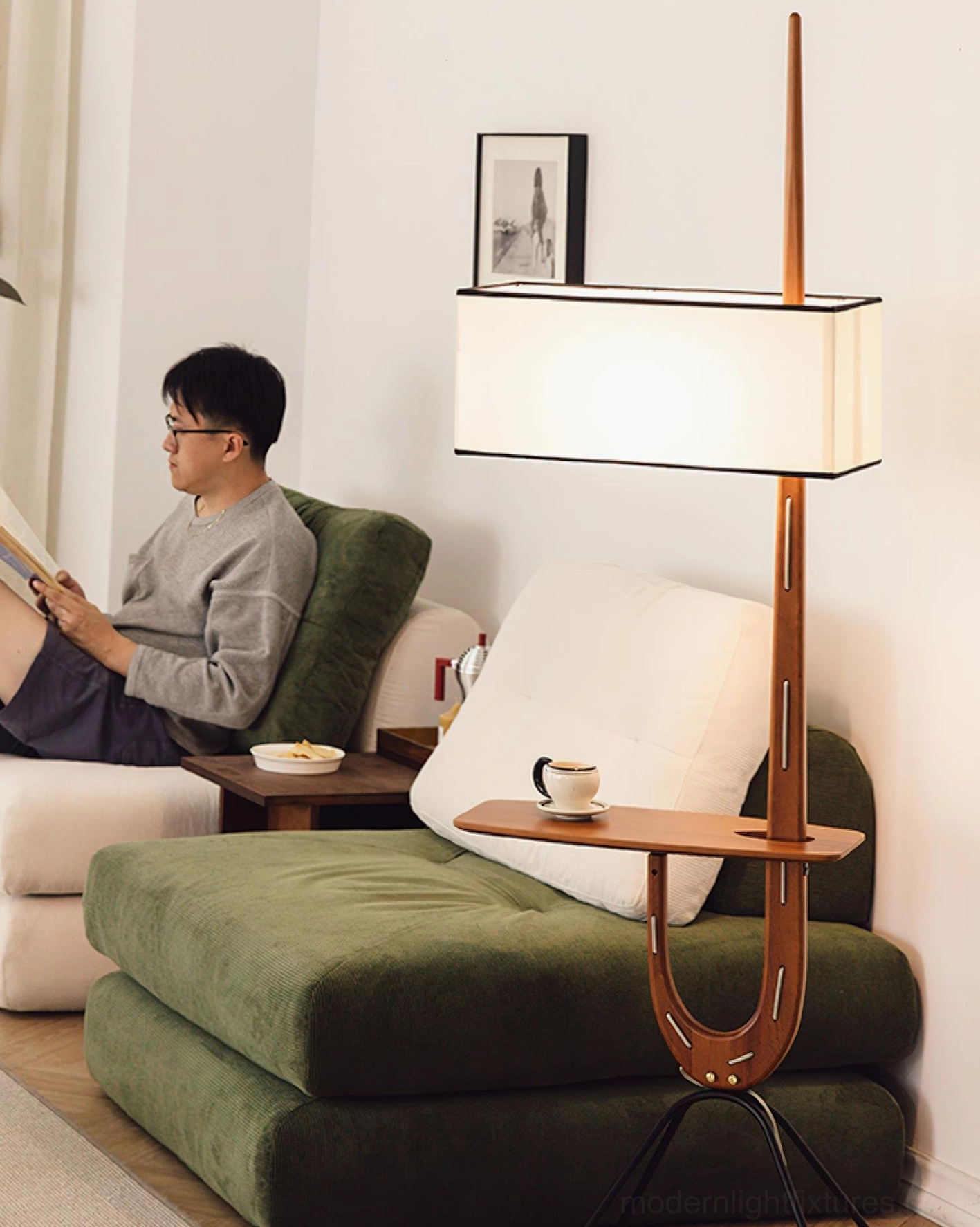 Modern wood floor lamp with side shelf in living room setting with man reading, snacks on shelf