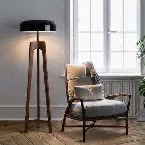 Contemporary wooden tripod floor lamp with black shade in cozy living room setting - side profile