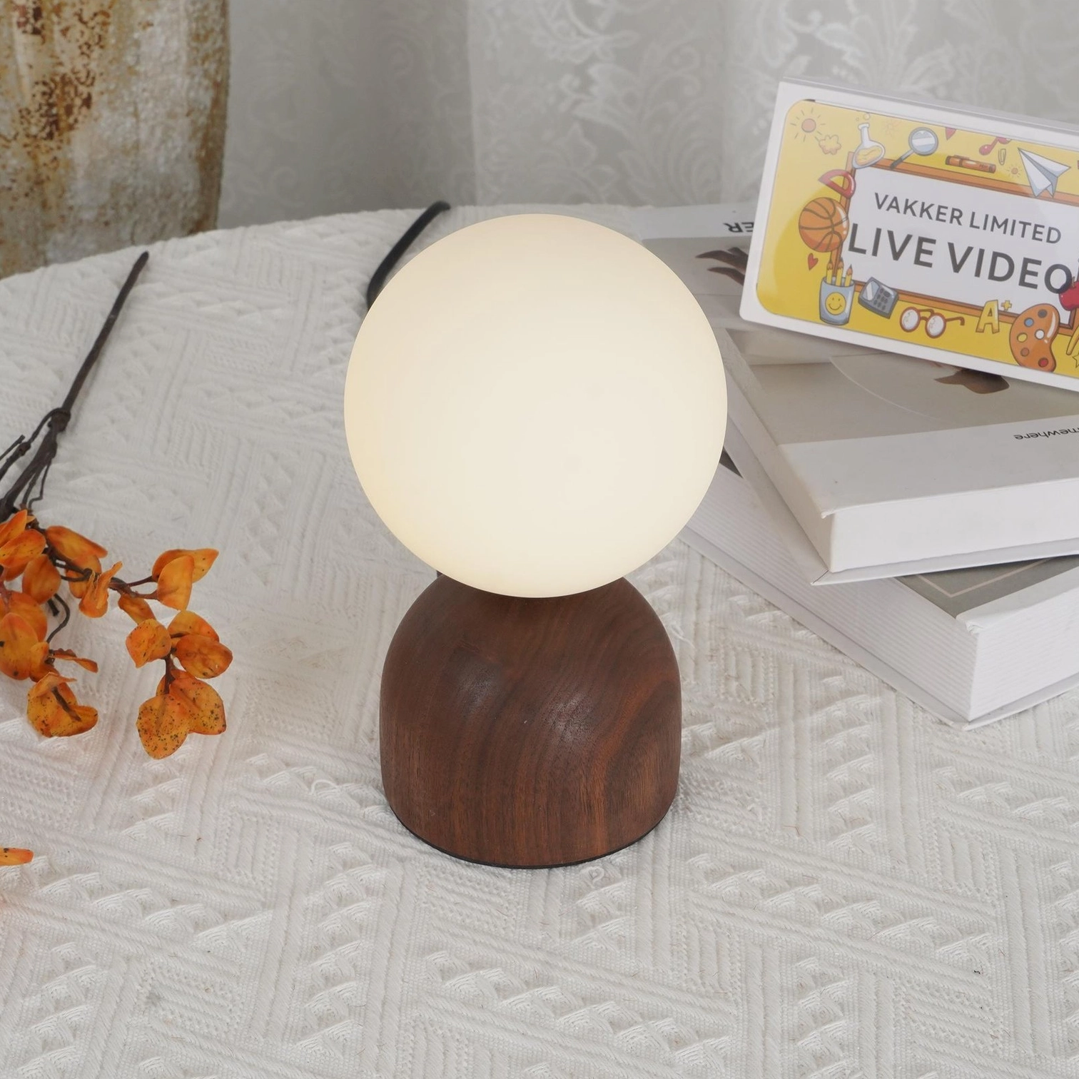 Contemporary walnut wood globe lamp on cozy knitted tablescape with black power cord visible