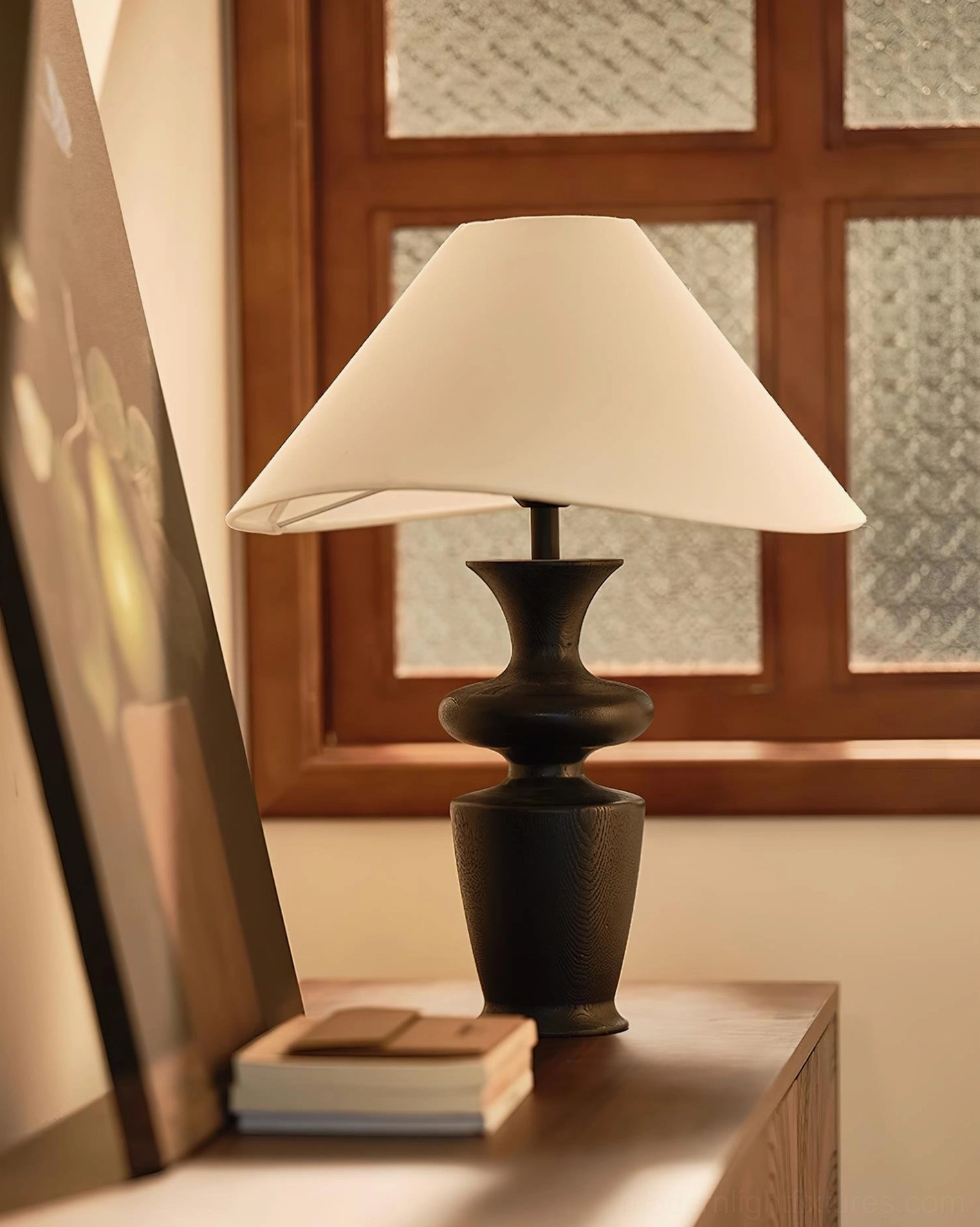 Minimalist wood table lamp on wooden console table next to framed artwork and stacked books, eye-level side view home decor