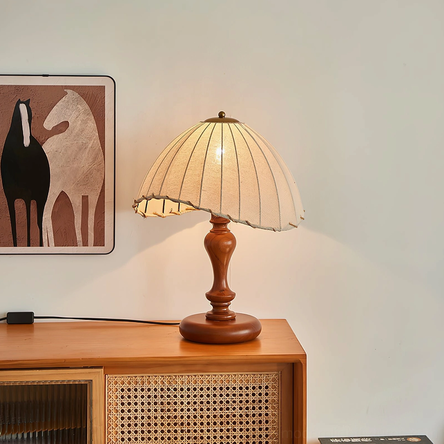 Classic turned wood pedestal base with pleated linen shade illuminated, three-quarter perspective