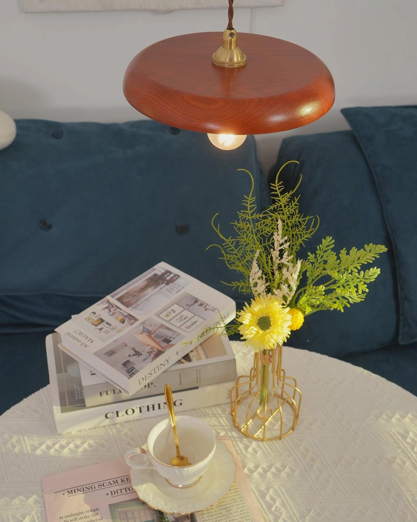 Warm wood pendant light above cozy lounge seating with tufted sofa and decorative coffee table
