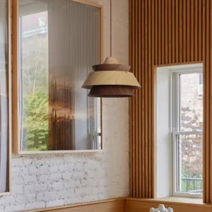 Layered wooden pendant light installed in residential kitchen nook with brick wall, eye-level perspective showing warm wood finish