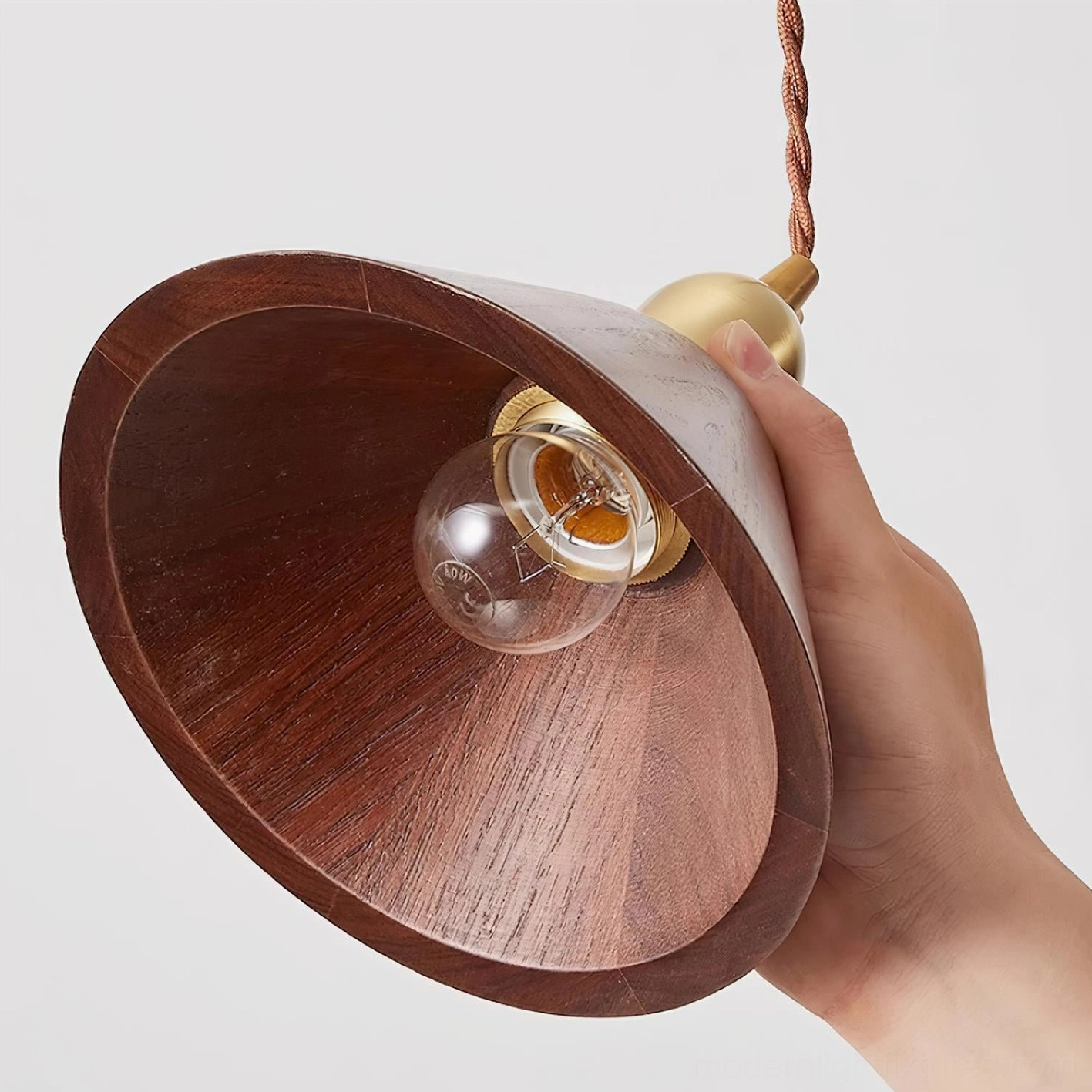 Close-up detail of walnut wood pendant shade with brass socket and twisted cord