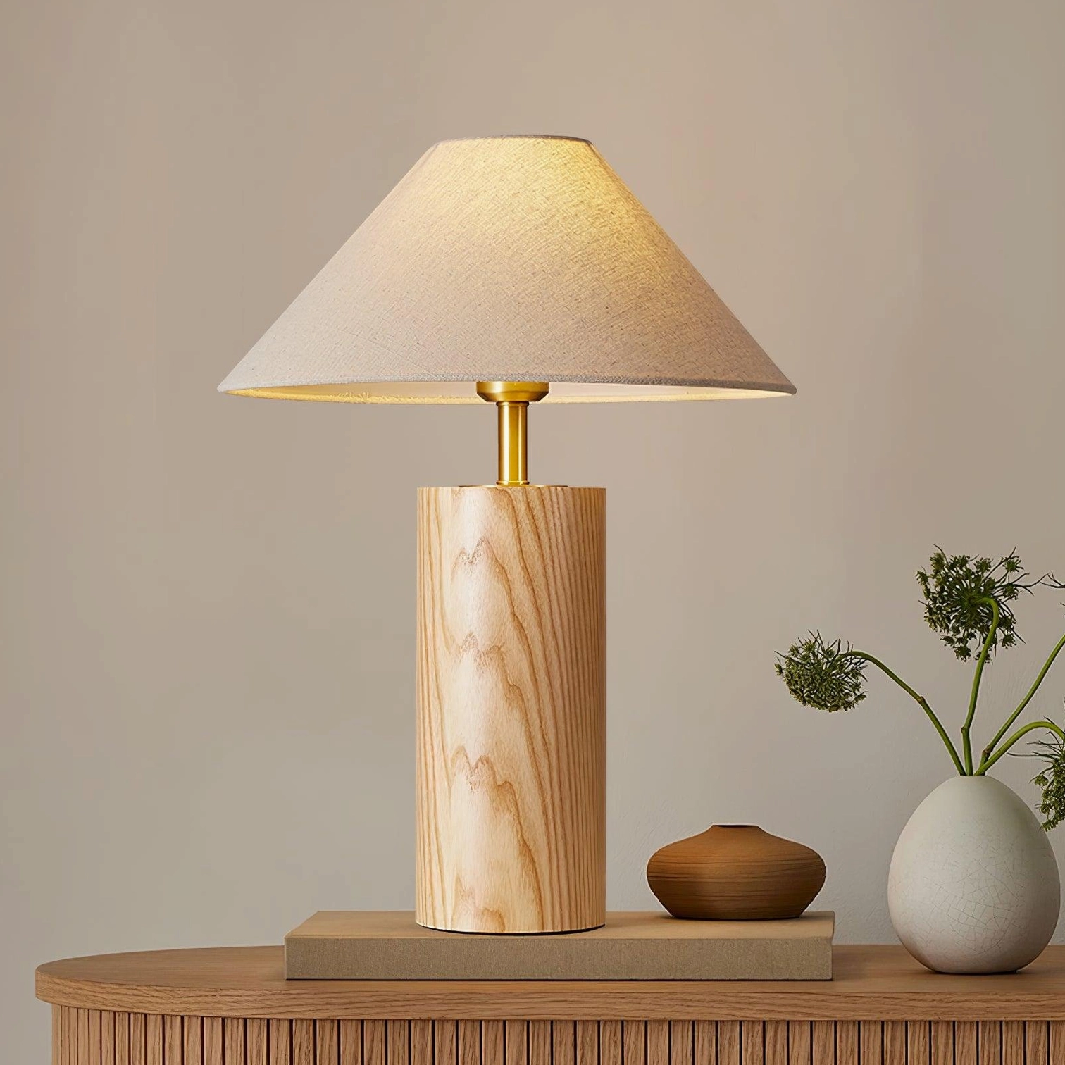 Natural wood cylindrical desk lamp displayed on wooden sideboard with home decor accessories