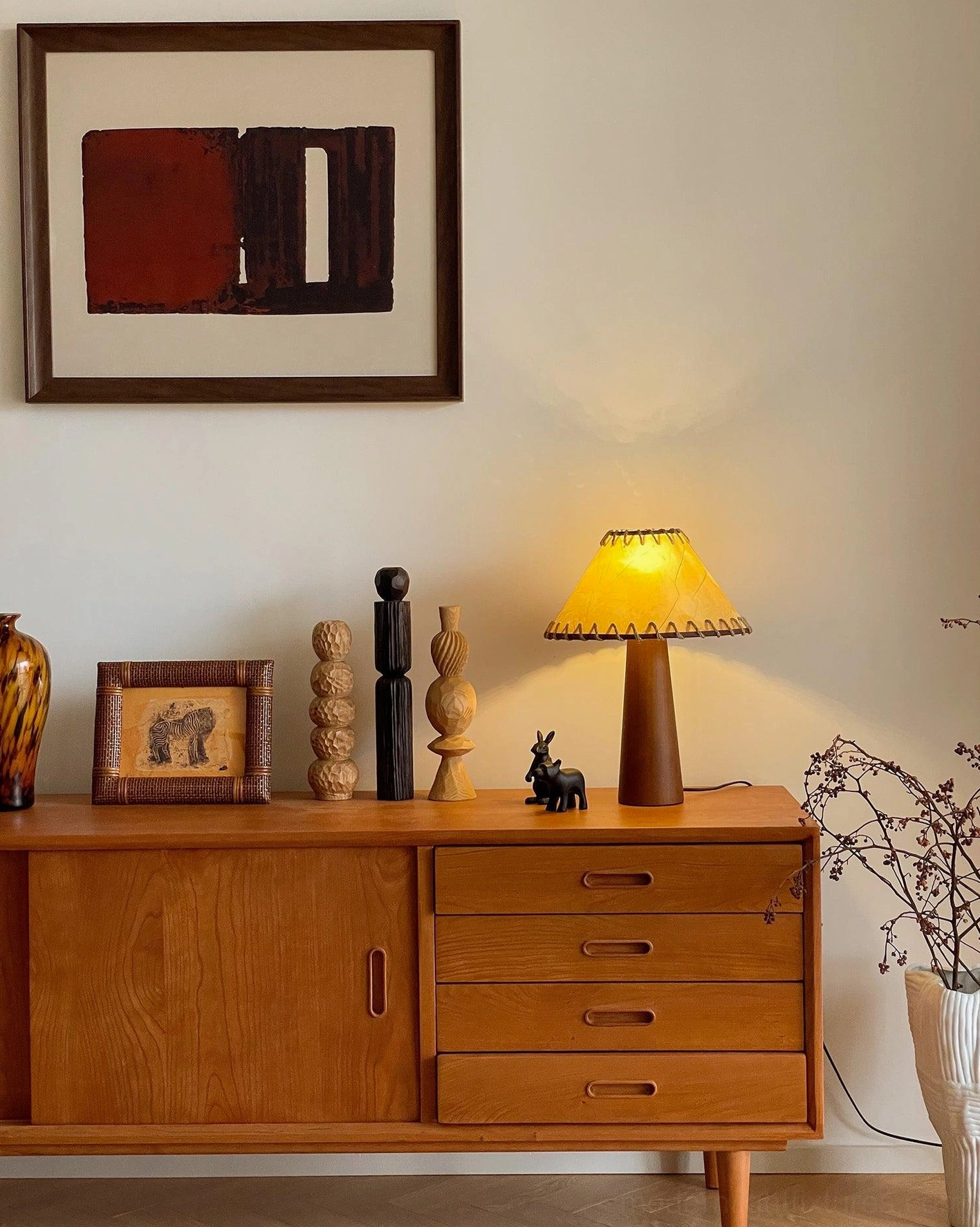 Illuminated wooden table lamp emitting warm glow on vintage sideboard with mid-century decor at nighttime