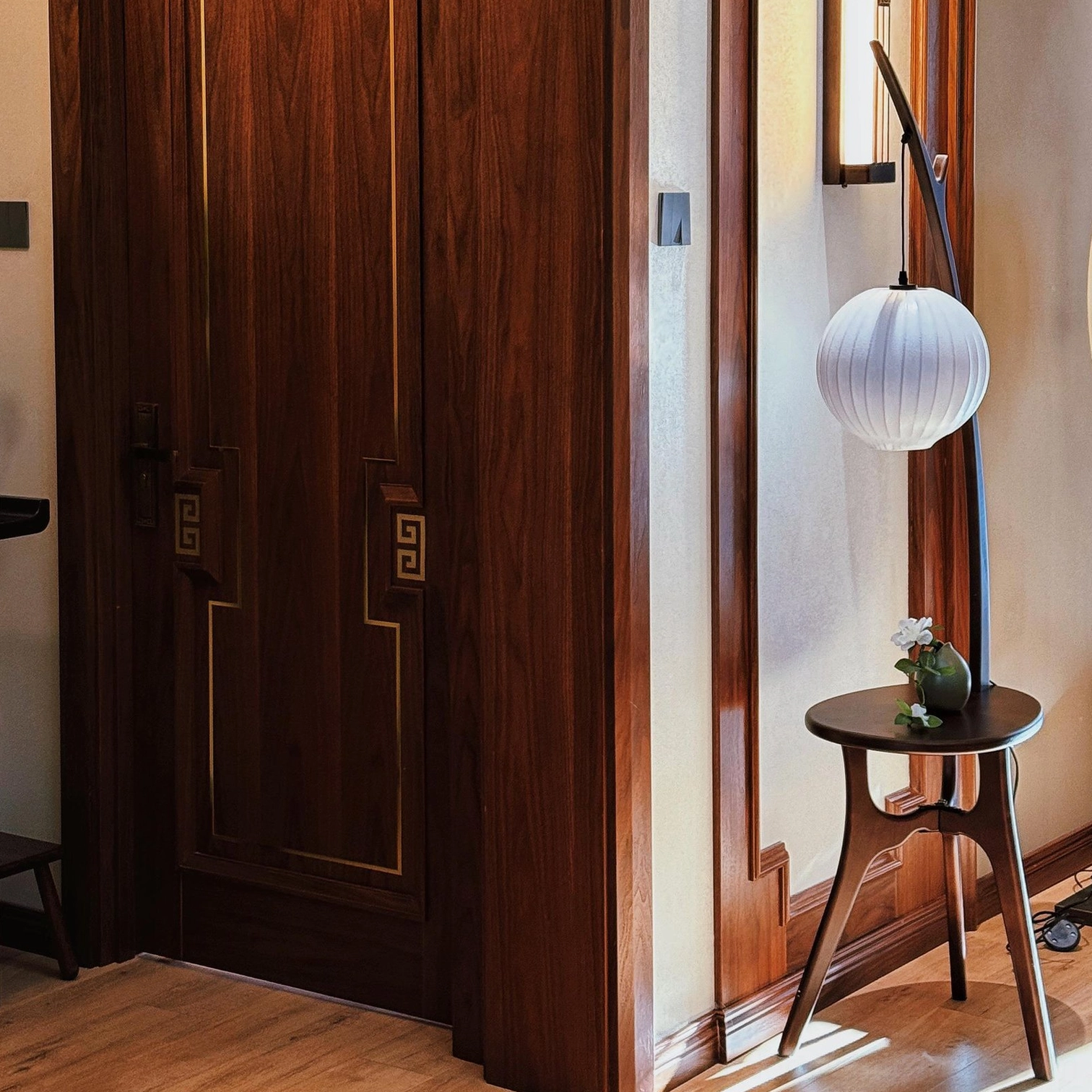 Artisanal wooden floor lamp with side table and white fabric shade in traditional entryway setting