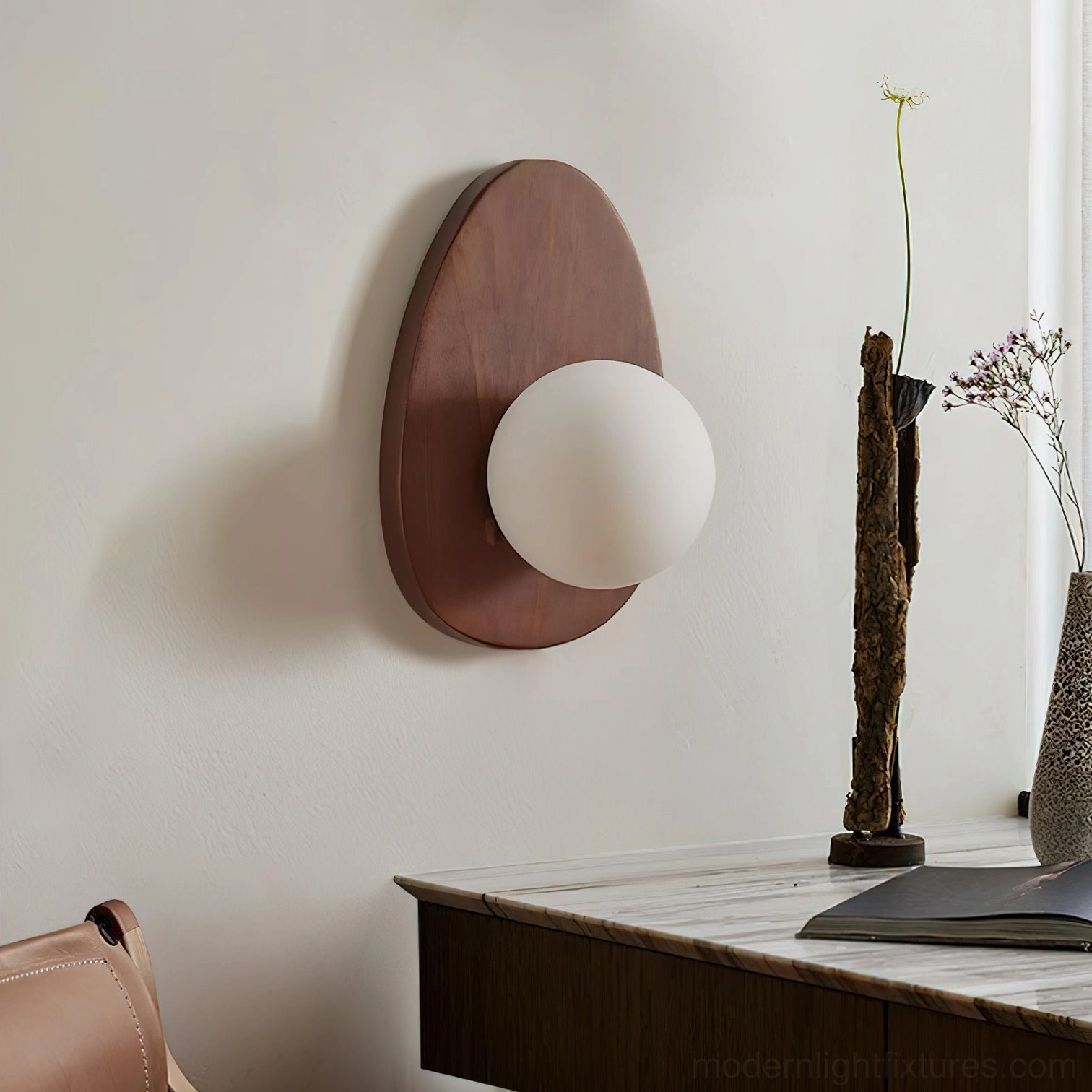 Walnut globe wall light unlit over bedroom dresser with dried floral arrangement, minimal styling