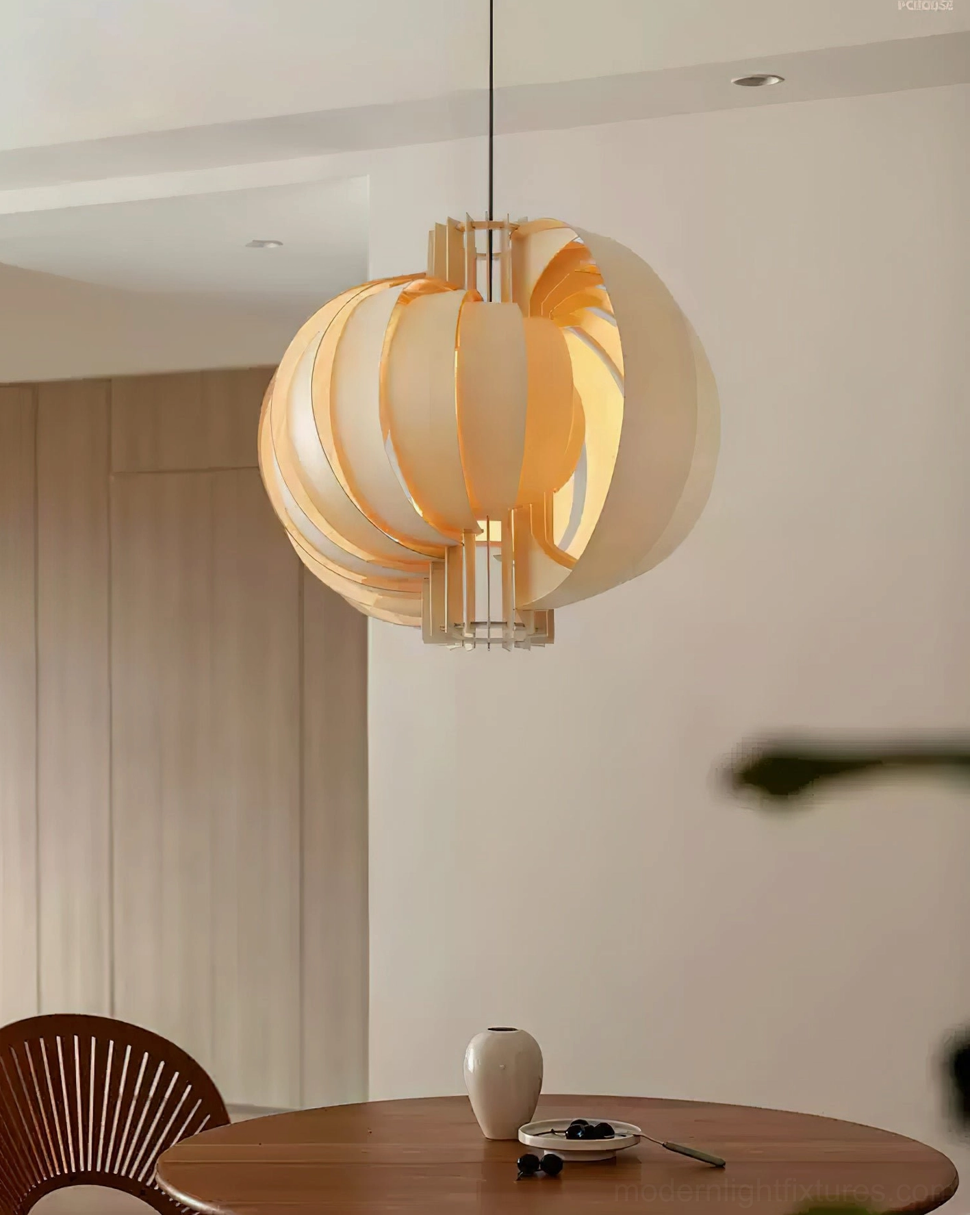 Lit wooden lantern pendant light glowing warmly above modern dining room table with wooden furniture