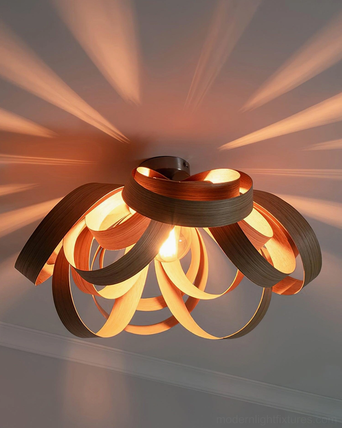 Two-tone wooden petal ceiling fixture casting radial light patterns upward view