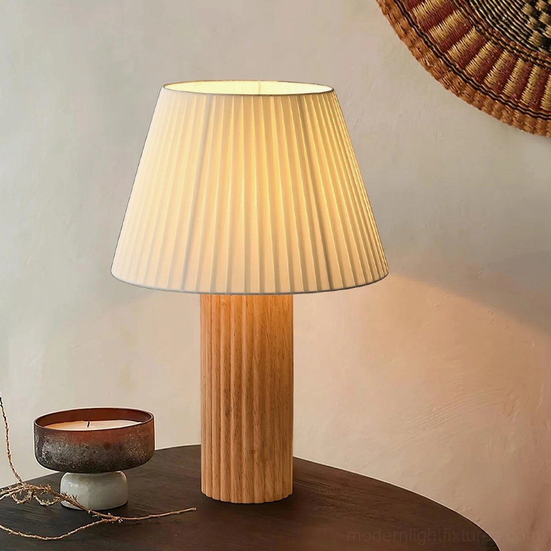 Contemporary wooden ribbed base table lamp with warm glowing pleated shade in mid-century rustic interior living room setting beside candle decor