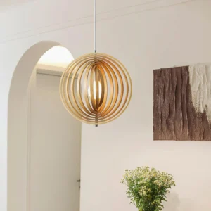 Wooden sphere pendant light illuminated in contemporary minimalist entryway with warm natural wood finish