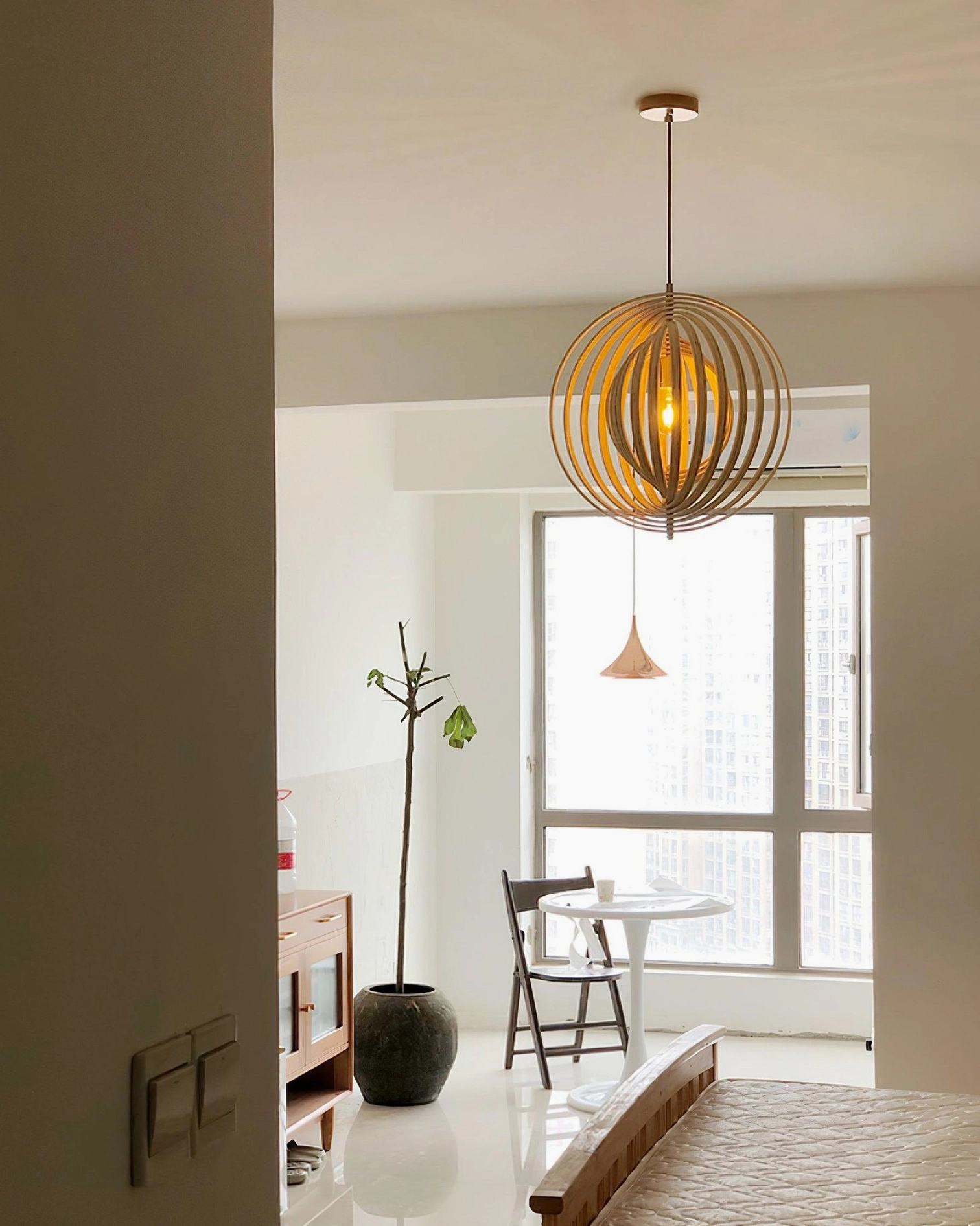 Modern wooden pendant lamp creating dramatic shadow patterns on ceiling in contemporary interior