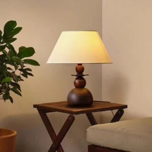 Walnut wood table lamp placed on wooden side table in bright living room, warm light glowing through fabric shade