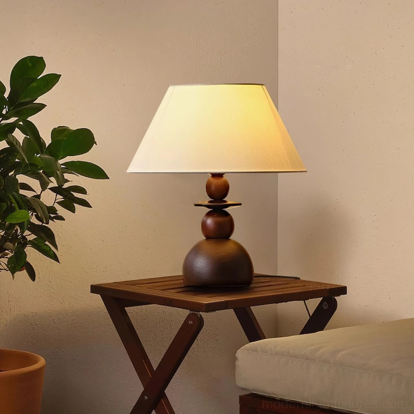 Walnut wood table lamp placed on wooden side table in bright living room, warm light glowing through fabric shade