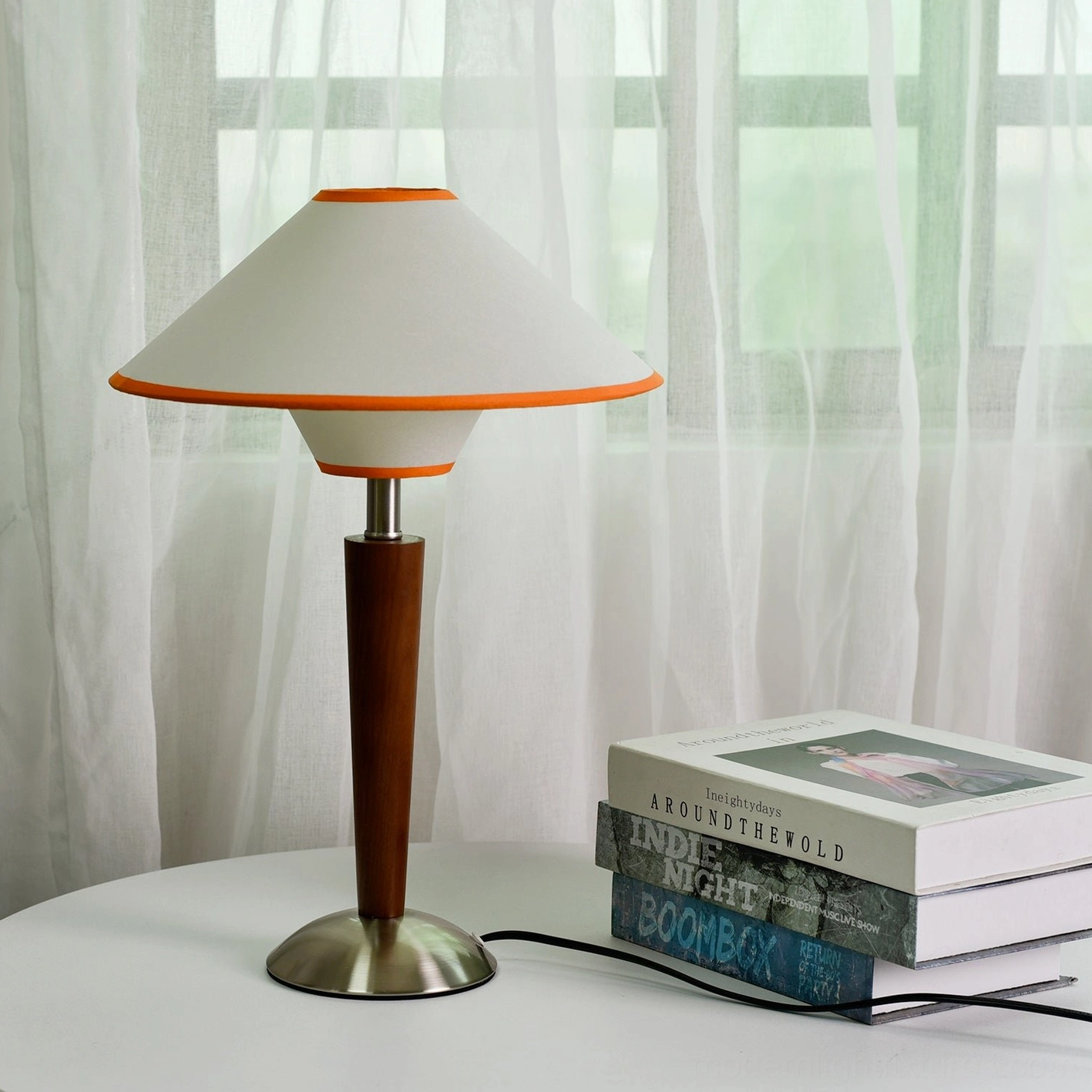 Modern wooden table lamp displayed on white round side table with coffee table books in home interior