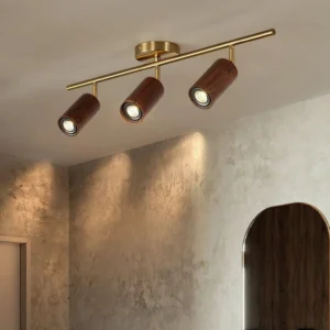 3-head adjustable wooden track lighting installed in modern concrete interior with warm brass finish