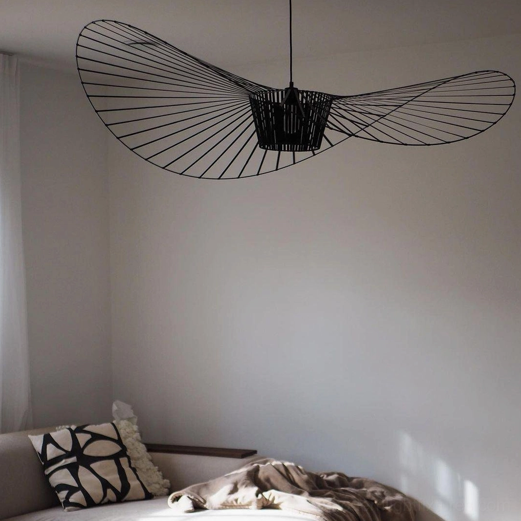 Low-angle view of woven fiber glass pendant with radial wire shade structure in cozy bedroom lounge area