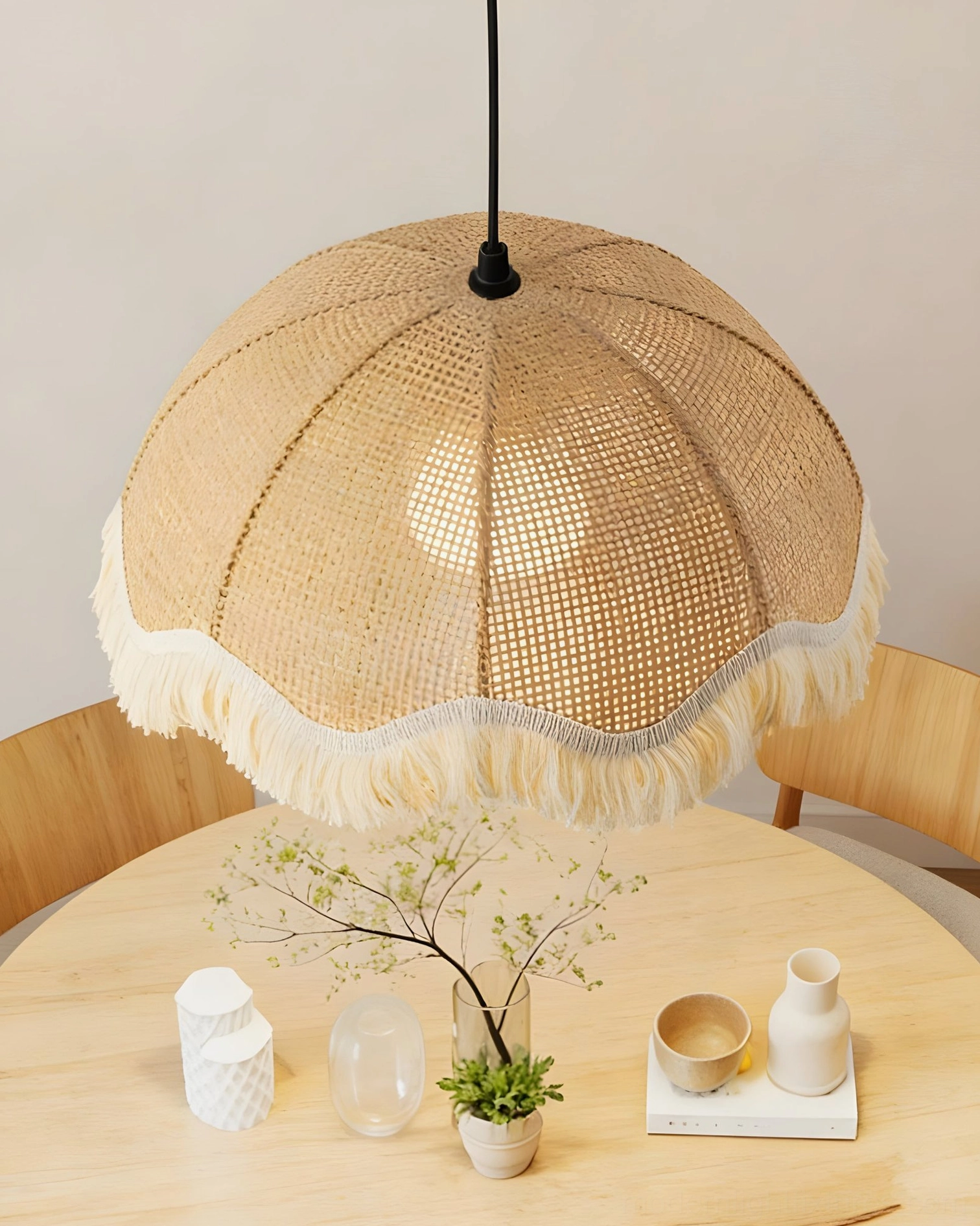 Overhead view of woven rattan fringe pendant light above dining table setting, full rattan shade with bottom tassel trim detail