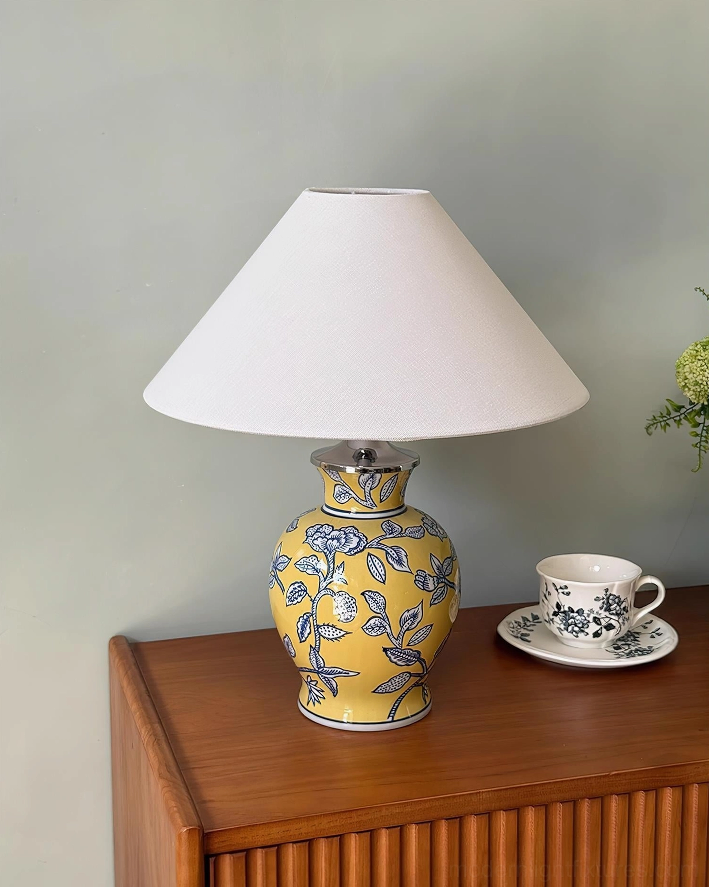 Yellow ceramic floral table lamp with blue botanical design and fabric shade, coffee table styling home scene