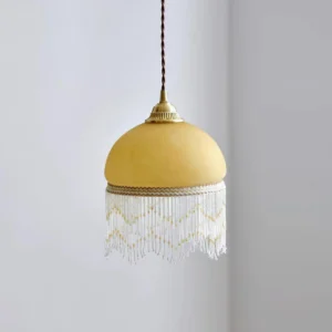 Yellow glass dome pendant lamp with brass hardware and chevron beaded tassel, three-quarter interior view