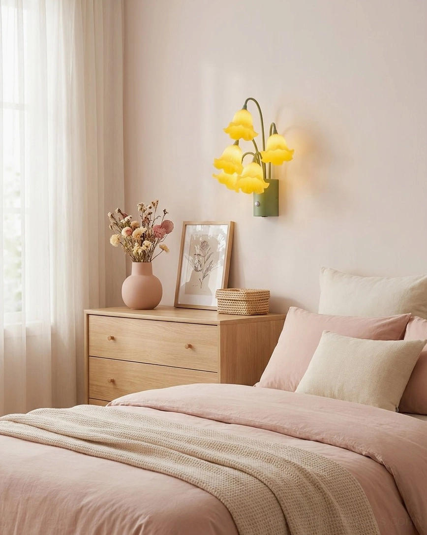 Yellow botanical wall sconce in pink bedroom interior above wooden nightstand bedside lighting