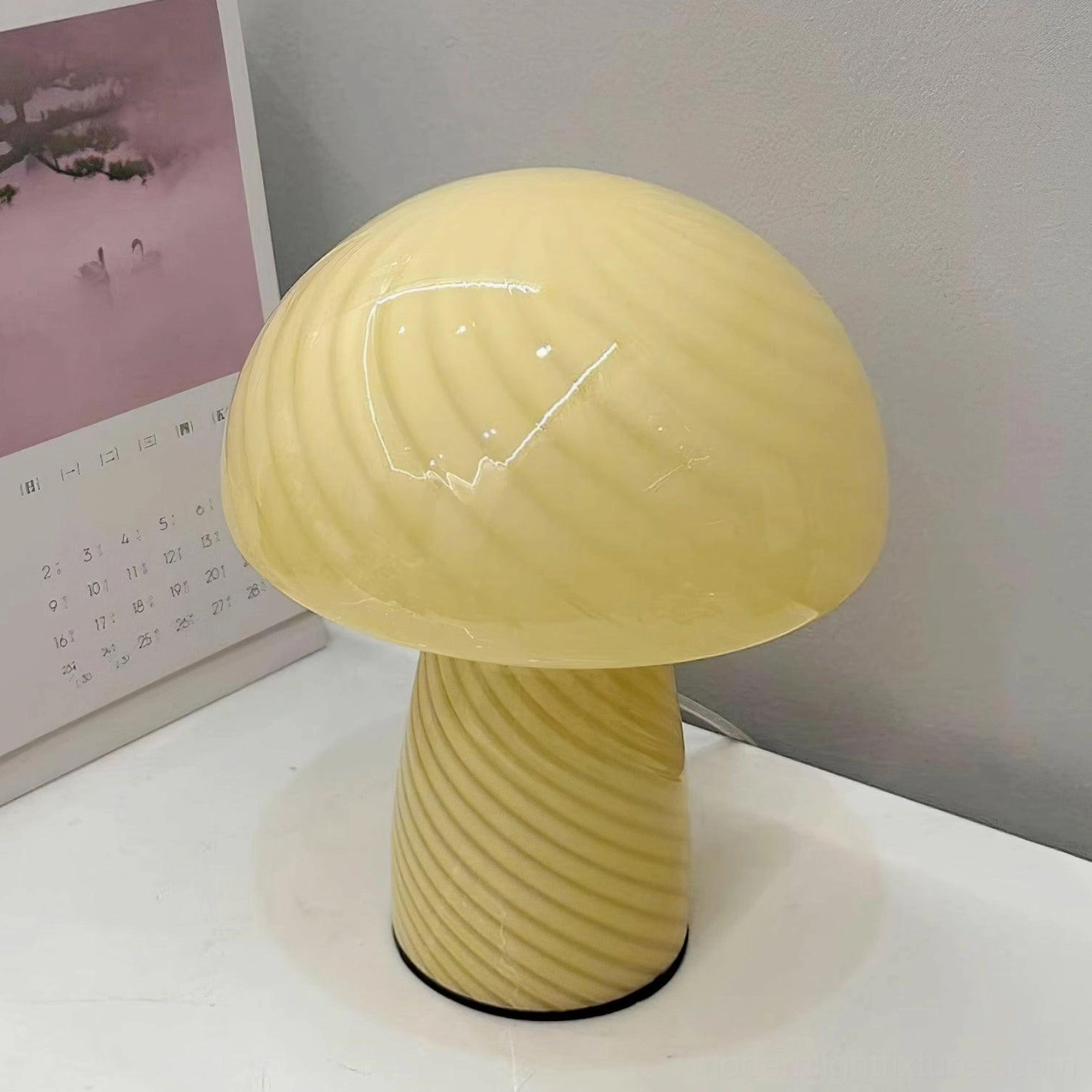 Cream yellow pastel striped mushroom glass table lamp front view on desktop with calendar