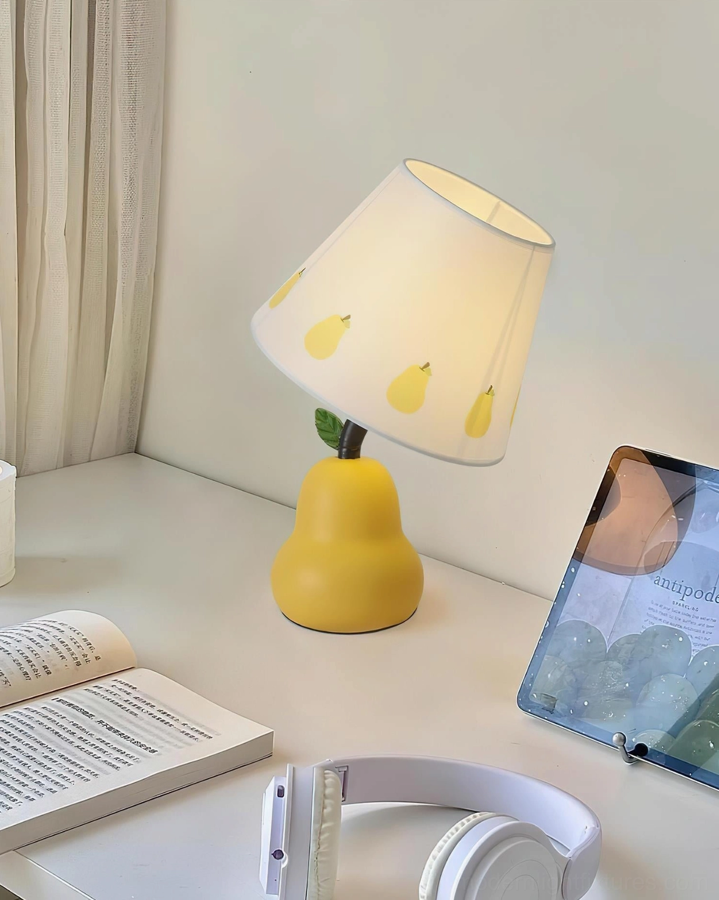Yellow pear-shaped table lamp on home office desk with reading accessories and botanical styling