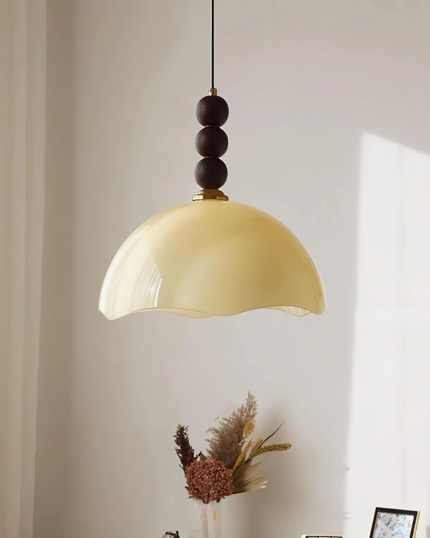 Front view of warm creamy yellow rippled glass pendant light showing smooth finish and neutral tone wood bead top