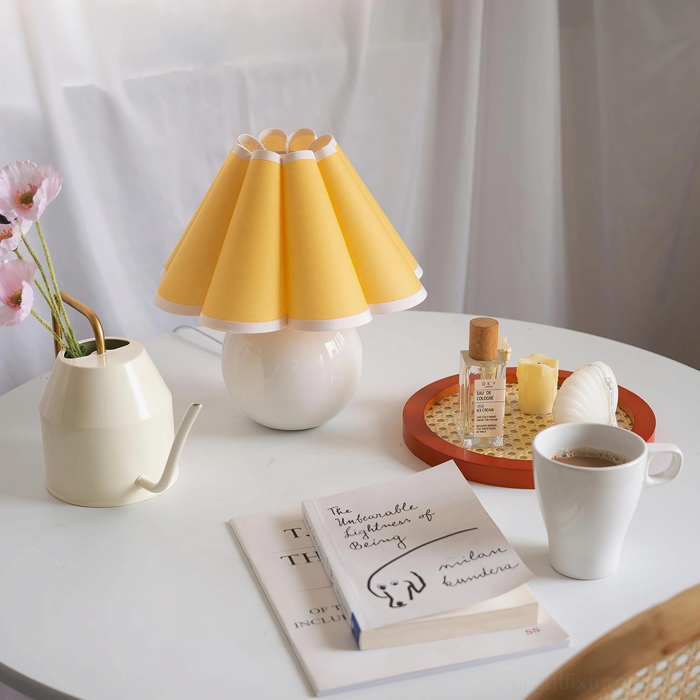 Yellow pleated fabric lamp with white ceramic base on round table with floral decorative accents