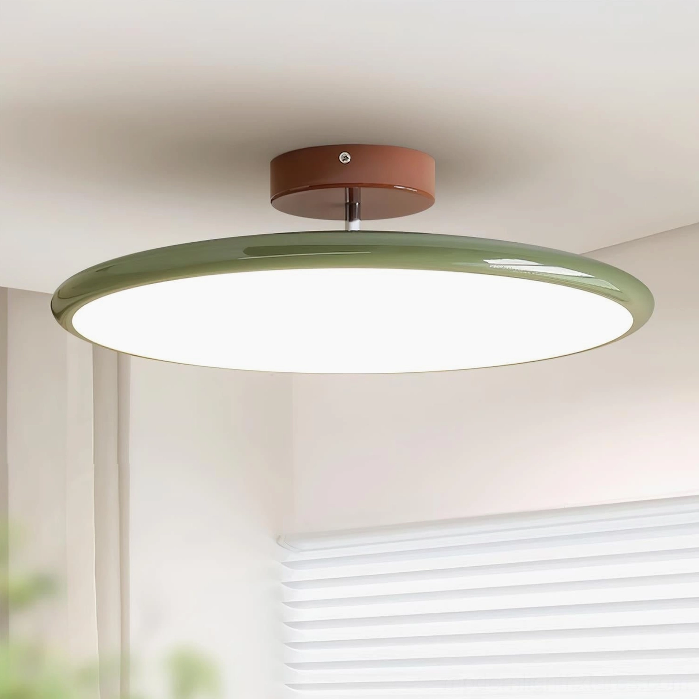 Zayn ceiling light installed in residential bedroom showing sage green disc with warm 3000K LED illumination above louvered window