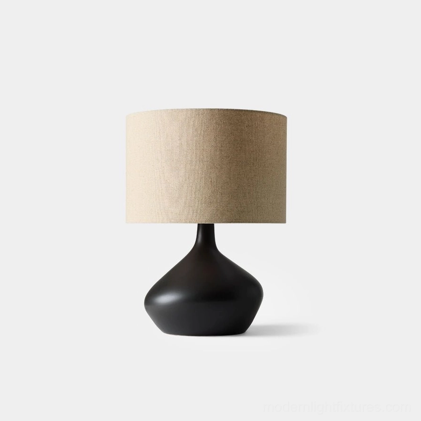 Matte black sculptural zen ceramic table lamp with beige linen drum shade, front studio view