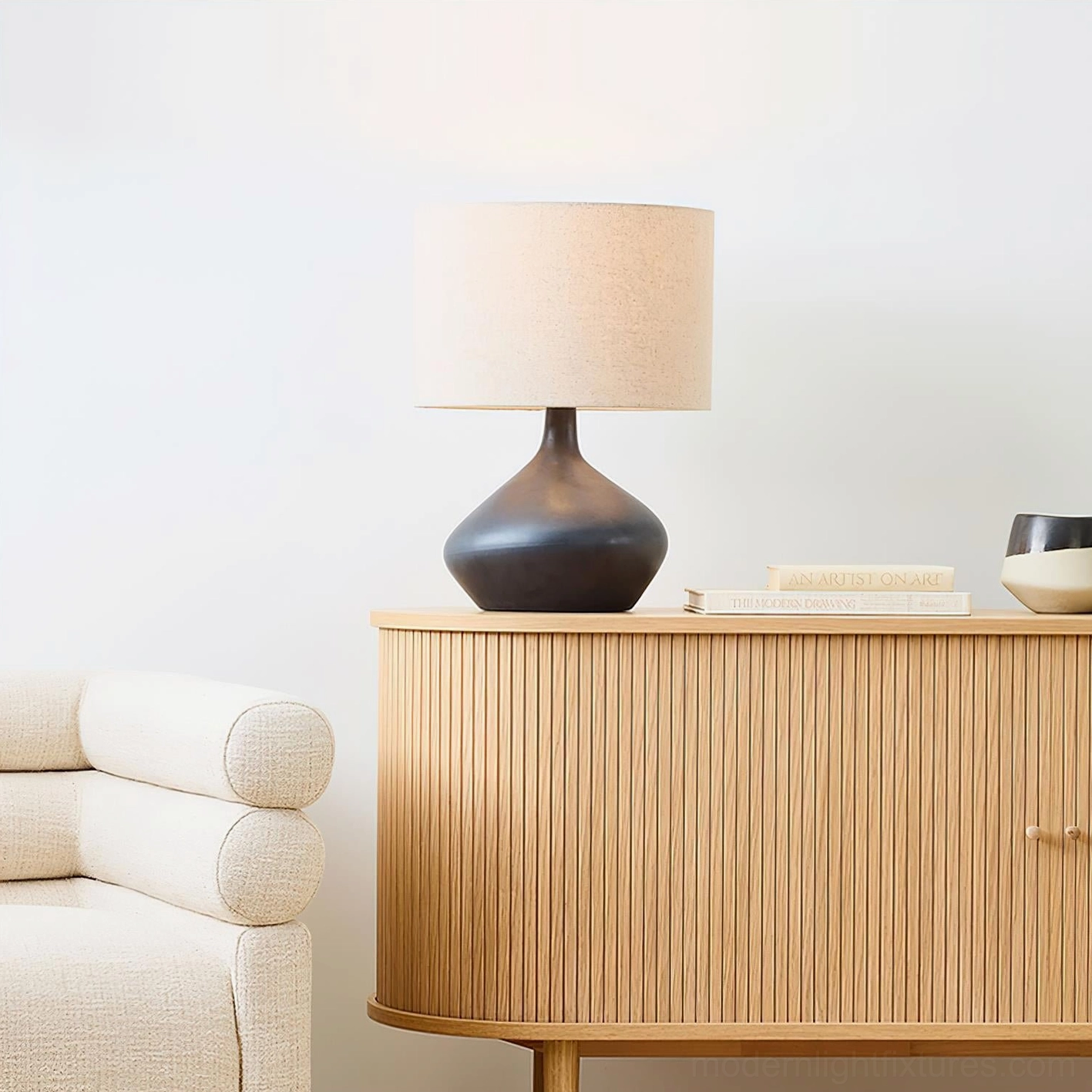 Sculptural zen table lamp with black curved ceramic base and off-white fabric shade in living room side cabinet setting