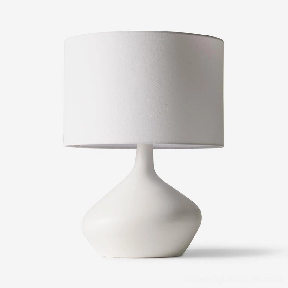 White minimalist sculptural zen table lamp with curved ceramic base and cylindrical fabric shade, studio front view