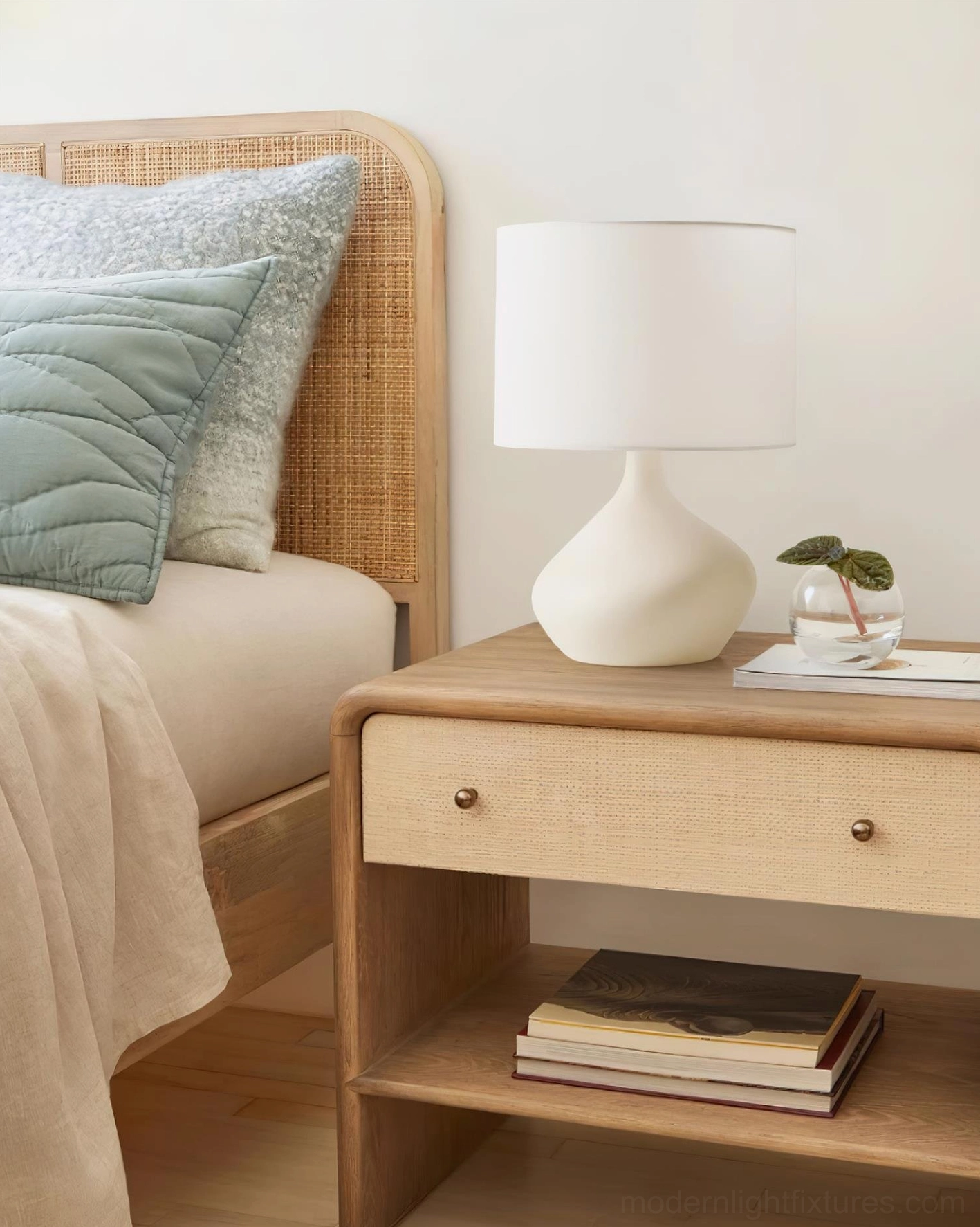 Matte white zen ceramic table lamp on bedroom nightstand with rattan headboard, minimalist bedroom décor