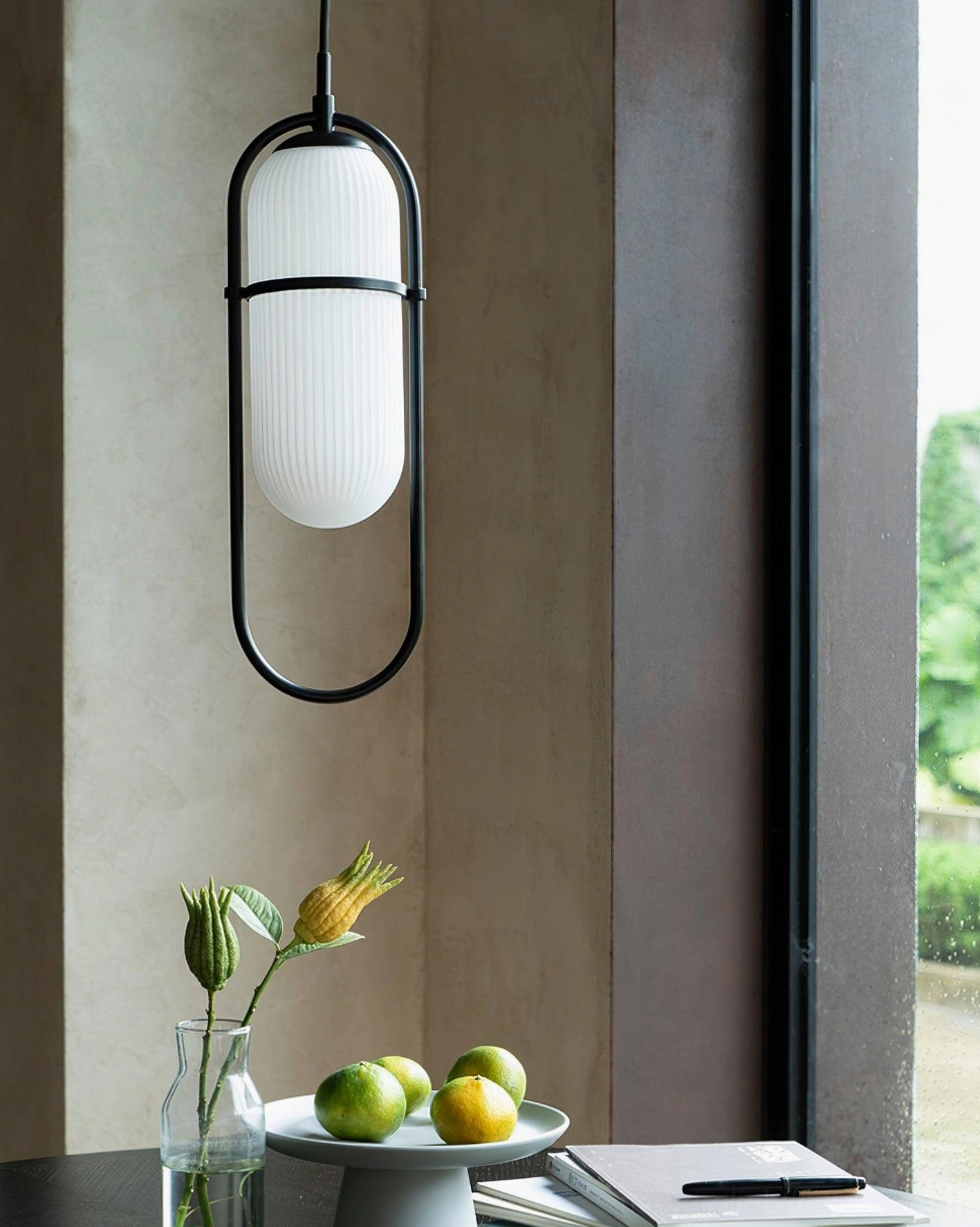 Zesta pendant light with black metal frame and frosted glass shade positioned above dining table nook