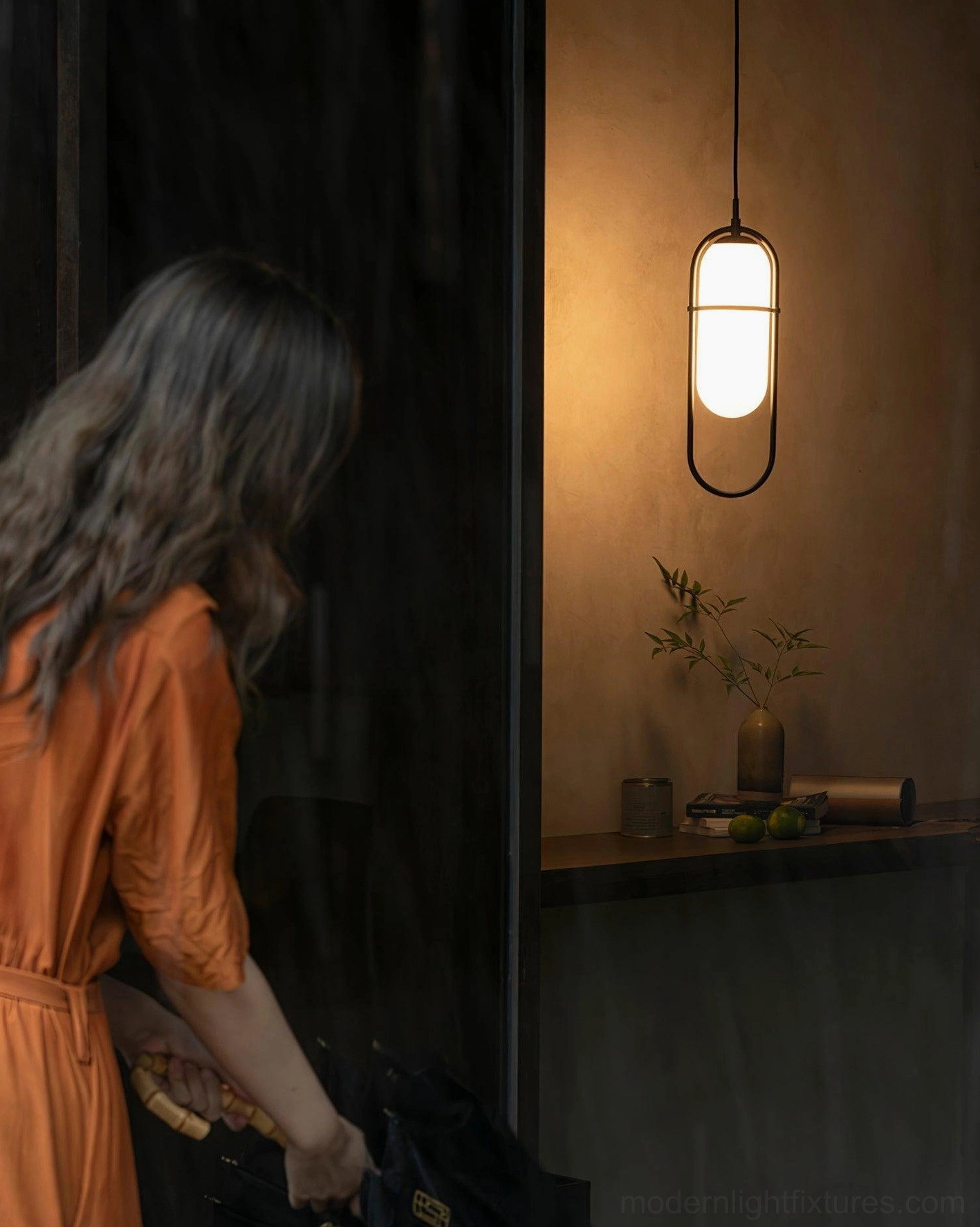Black Zesta pendant light mounted in residential entryway with warm ambient lighting and neutral wall