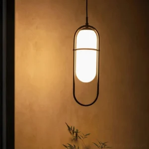 Black metal framed Zesta pendant lamp with illuminated frosted glass shade mounted on warm textured wall