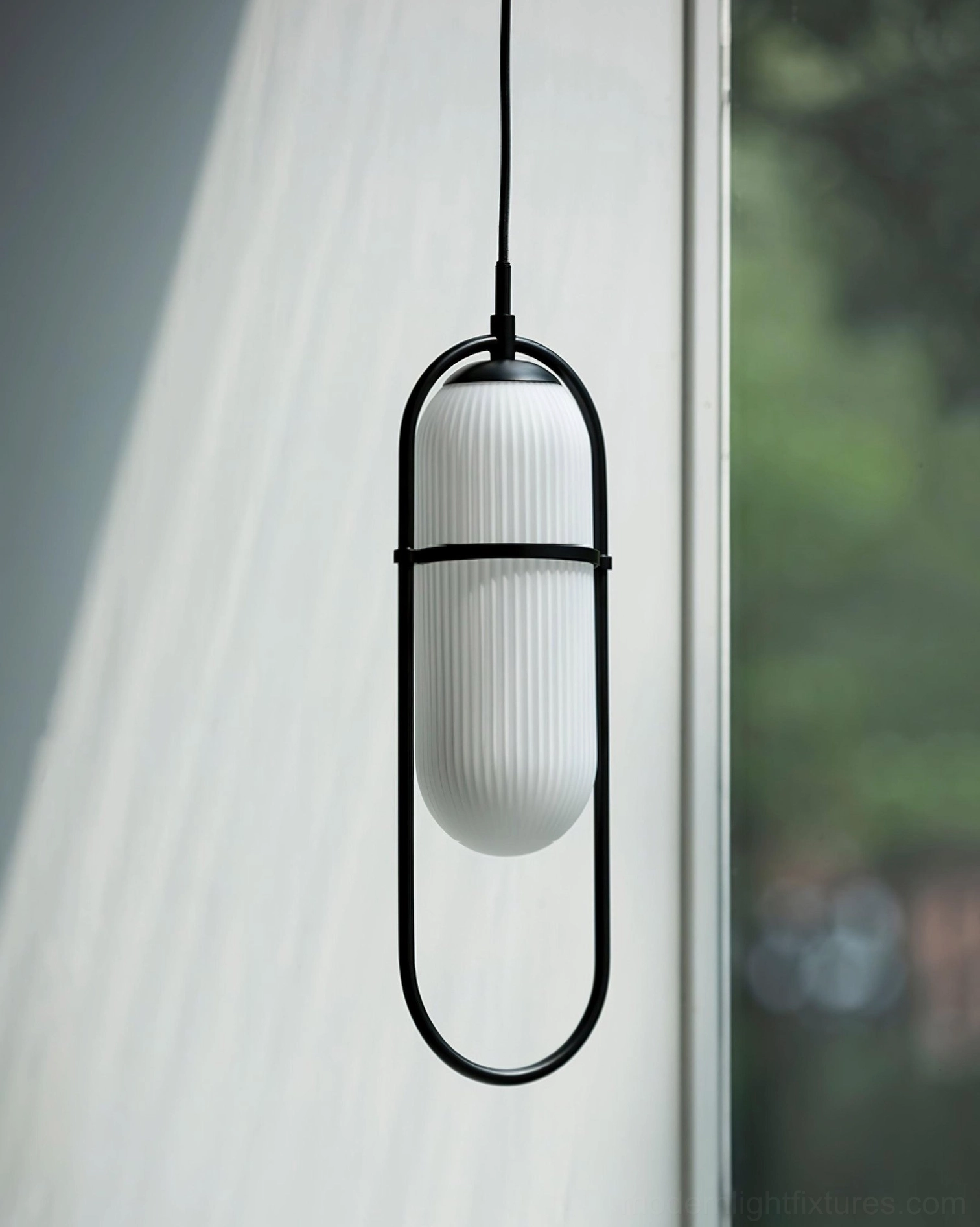 Zesta pendant light with black elongated oval metal frame and ribbed white glass shade, side profile view