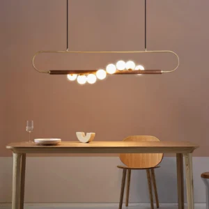 Zeta Linear Chandelier installed above warm wooden dining table with brass glow and natural wood tones in interior dining nook