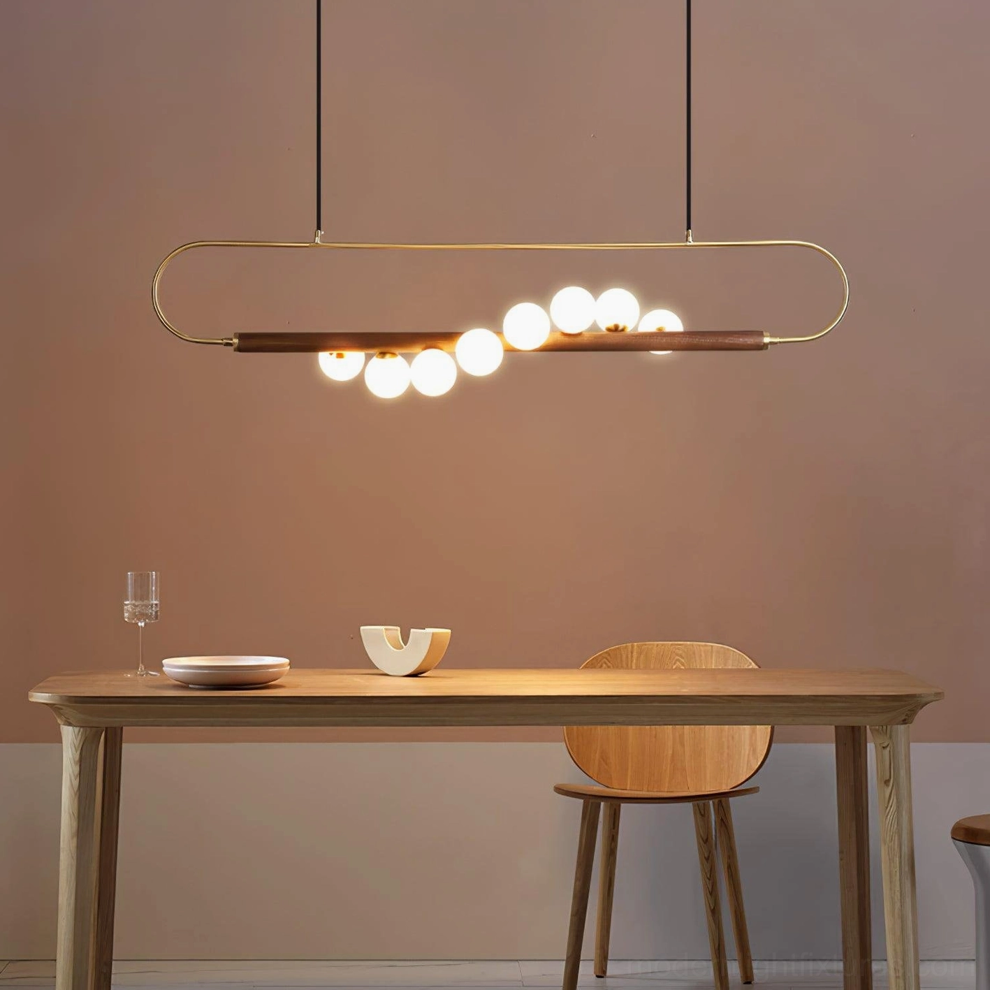 Zeta Linear Chandelier installed above warm wooden dining table with brass glow and natural wood tones in interior dining nook